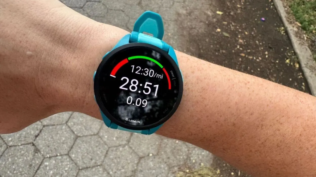 A Garmin watch on a wrist in the middle of a workout, showing pace, time and distance under a target gauge.